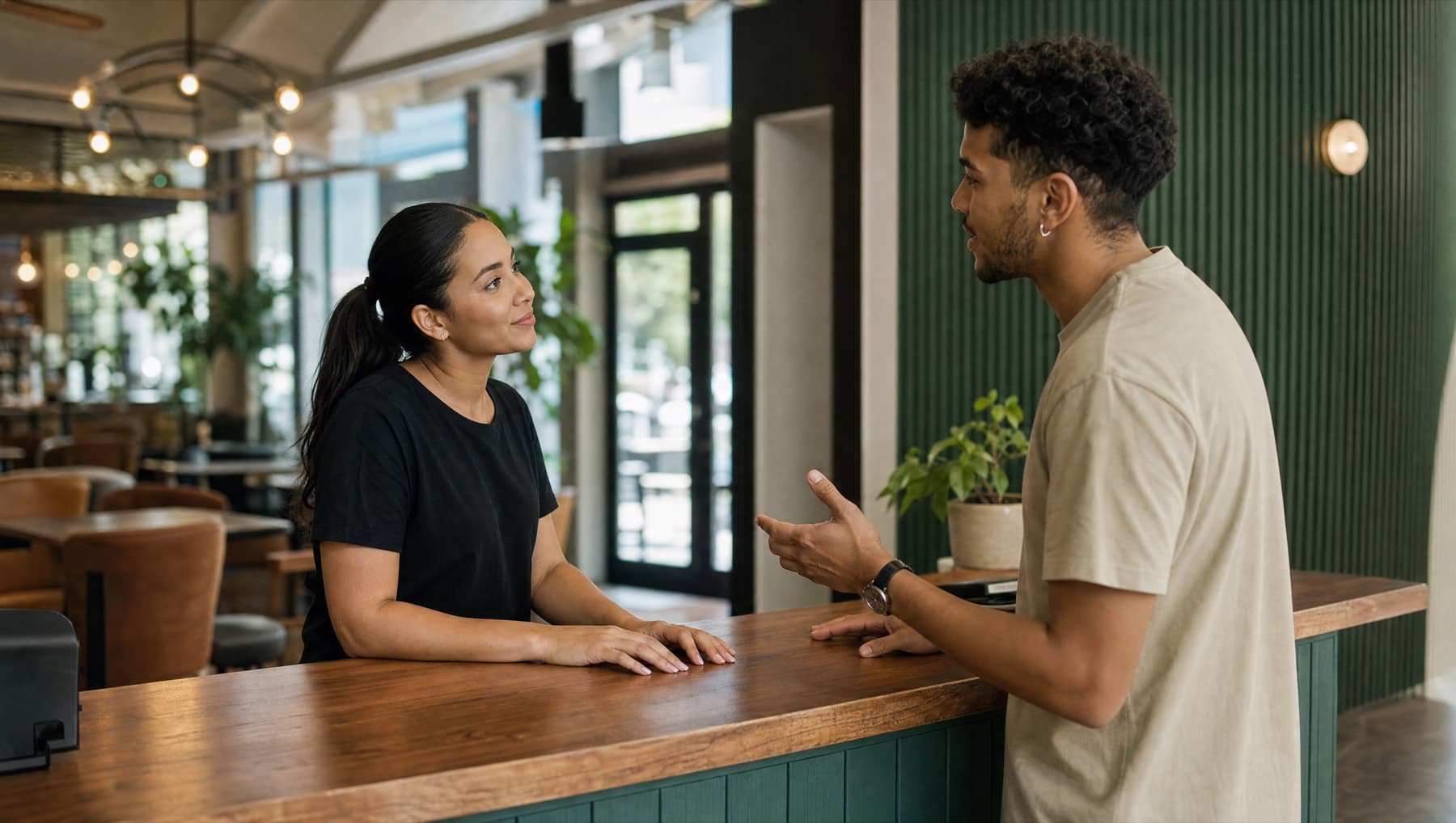 A staff member listening to a customer across the counter of a hospitality venue